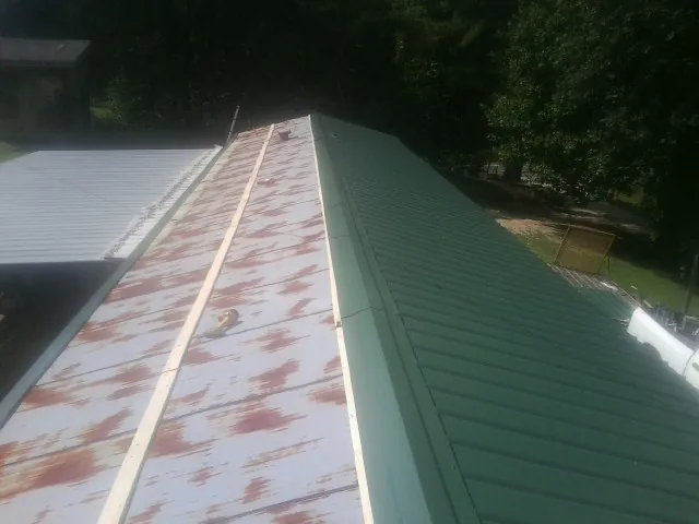 Old rusted panels beside newly installed green metal roofing — Wind Damage Roof Repair by Roofing Brothers in Sauk City