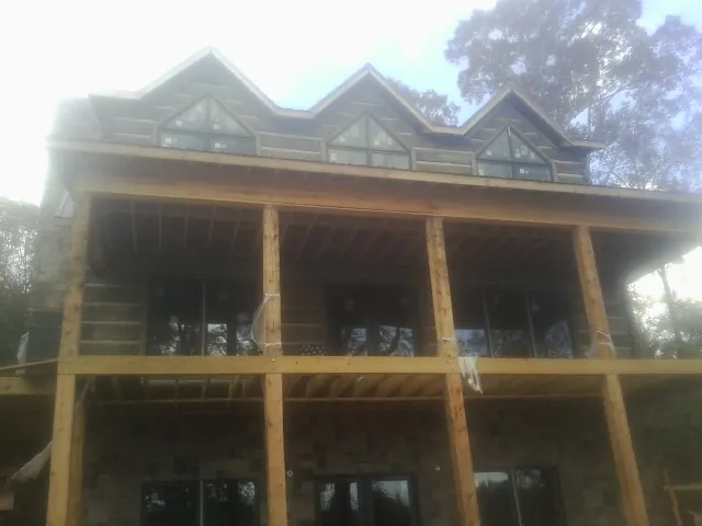 Dormers and porch framing on a large log home under construction — Roof Coating work by our crew in Sauk City
