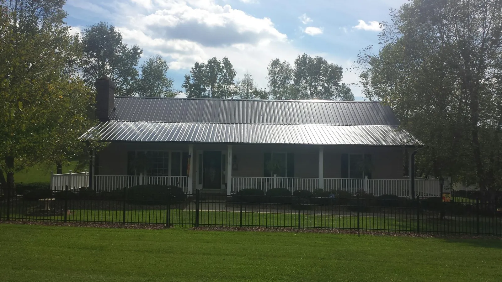 Gray metal roof on a brick ranch with a full width front porch — Gutter Guard Installation work by our crew in Sauk City