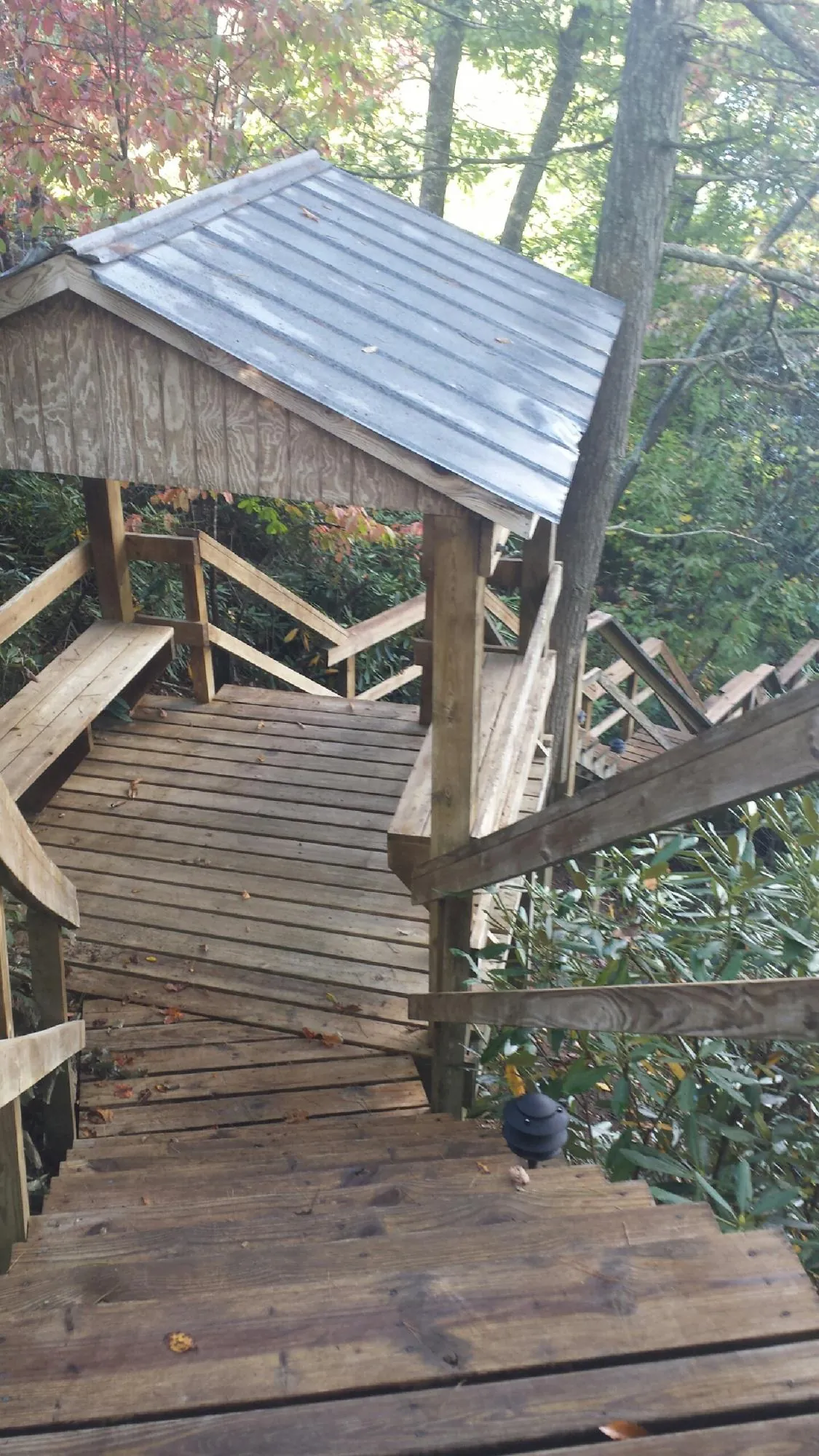 Metal roofed shelter over wooden steps on a wooded walkway — Skylight Repair & Installation work by our crew in Sauk City