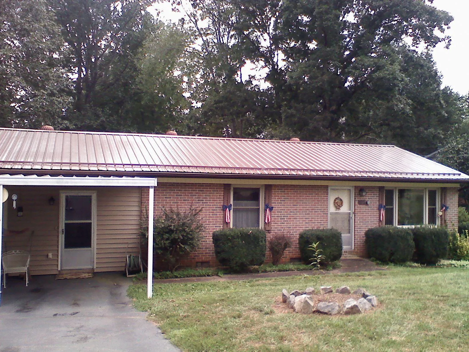 Bronze metal roof and carport on a brick ranch home — Roof Repair work by our crew in Sauk City
