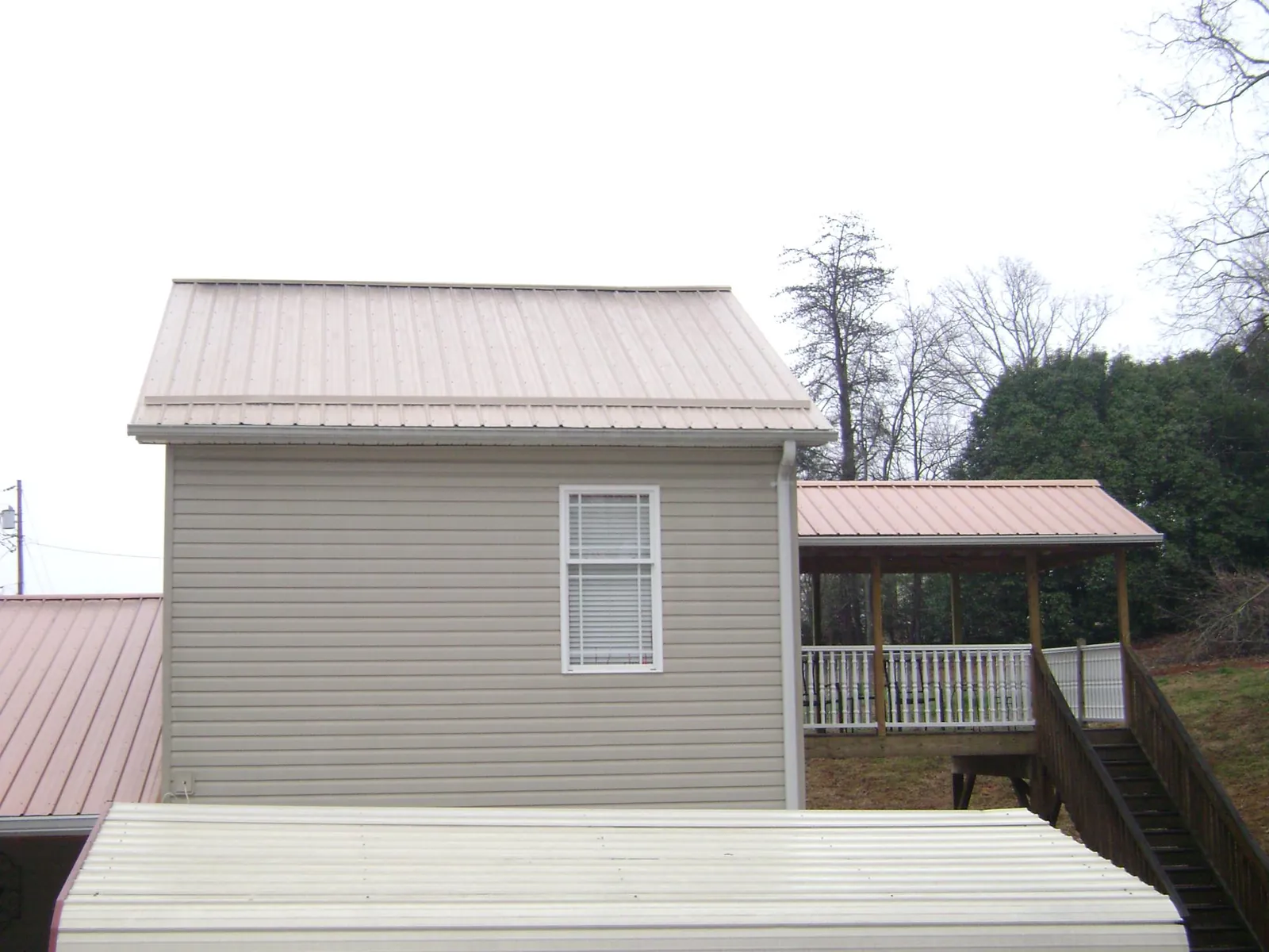 Tan metal roofs on a two story addition and attached porch, from a Roof Replacement job in Sauk City